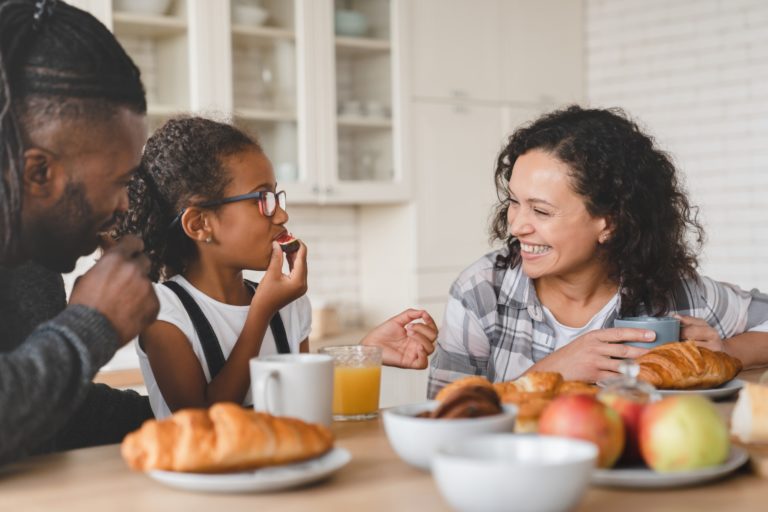 Family having breakfast, eating fruits at home kitchen, having fun together. Healthy eating. Bonding